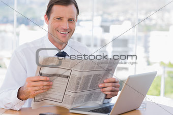 Cheerful businessman reading a newspaper
