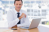 Smiling businessman leaning on his desk