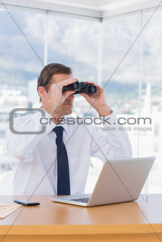 Businessman using binoculars while he is working
