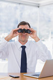 Businessman using binoculars in front of the camera