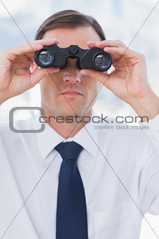 Serious businessman using binoculars