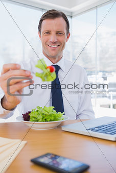 Cheerful businessman eating a salad