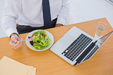Overhead of a businessman eating a salad on his desk