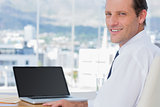 Cheerful businessman sitting in front of a laptop