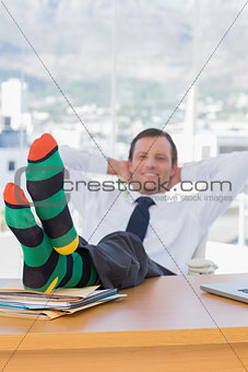 Happy businessman relaxing with feet on his desk