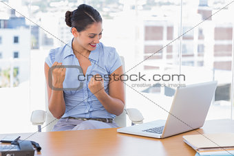 Brunette businesswoman cheering in front of her laptop