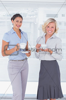Two colleagues holding cup of coffee