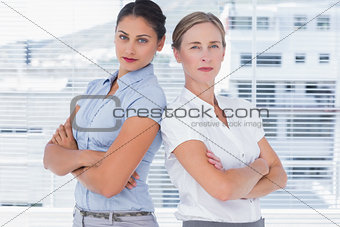 Stern businesswomen standing back to back