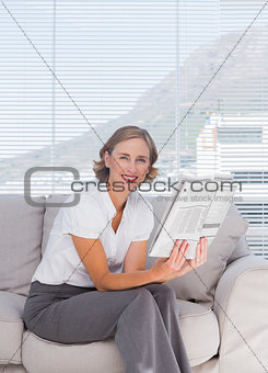 Businesswoman sitting on couch and holding newspaper