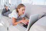 Businesswoman lying on couch and using laptop