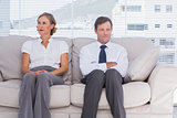 Two bored business people sitting on couch