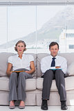 Stern business people sitting on couch