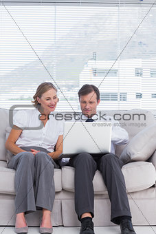 Businessman and woman sitting on couch