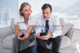 Businessman showing his mobile phone to colleague