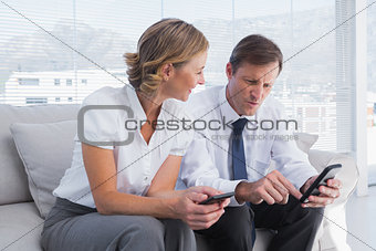 Attractive businessman showing something on his mobile phone to a businesswoman