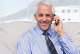 Businessman calling on smartphone and smiling at camera