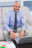 Businessman working with his laptop and smiling at camera