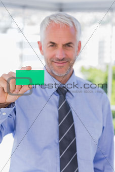 Smiling businessman showing green business card
