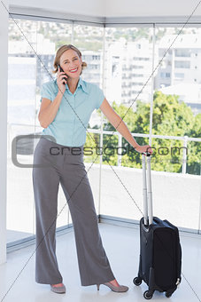 Smiling businesswoman on the phone with suitcase