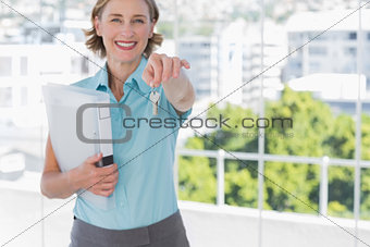 Estate agent showing house keys and smiling at camera