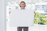 Happy businesswoman holding large white poster