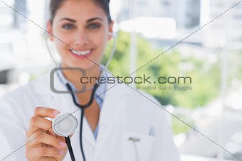 Pretty young doctor holding up stethoscope