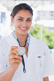 Happy young doctor holding up stethoscope