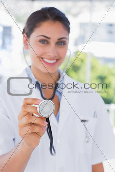 Happy young doctor holding up stethoscope