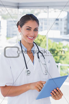 Smiling young doctor using tablet pc