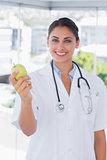 Pretty young doctor holding a green apple