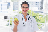 Smiling young doctor holding a green apple