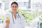 Smiling doctor holding a green apple