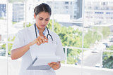 Doctor going through notes on clipboard
