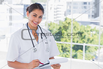 Doctor smiling and holding clipboard and pen