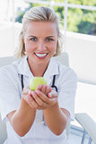 Blonde nurse holding a green apple