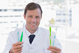 Smiling doctor holding two toothbrushes