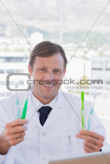 Cheerful doctor holding two toothbrushes