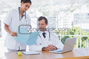 Doctor showing a folder to a colleague