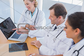 Smiling doctor showing laptop screen to colleagues