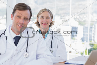 Cheerful group of doctors posing at their desk
