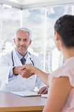 Cheerful doctor shaking hands to patient