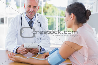 Smiling doctor taking the heartbeat of a patient