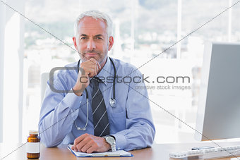 Cheerful doctor sitting behind his desk
