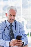 Doctor typing a text message on his smartphone