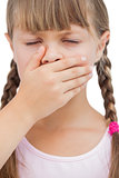 Little blond girl with her hand on her mouth with her eyes closed