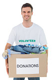 Attractive man holding donation box with clothes