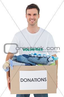 Attractive man holding donation box with clothes