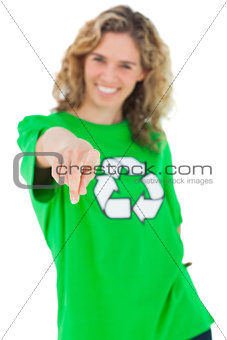 Smiling environmental activist wearing green shirt with recycling symbol on it and pointing the came