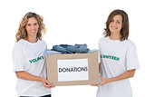 Two cheerful volunteers carrying clothes donation box