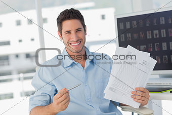 Cheerful photo editor pointing at documents